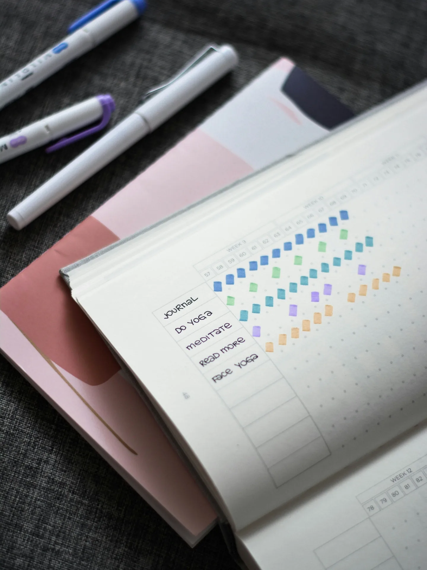An open habit-tracking journal with markers